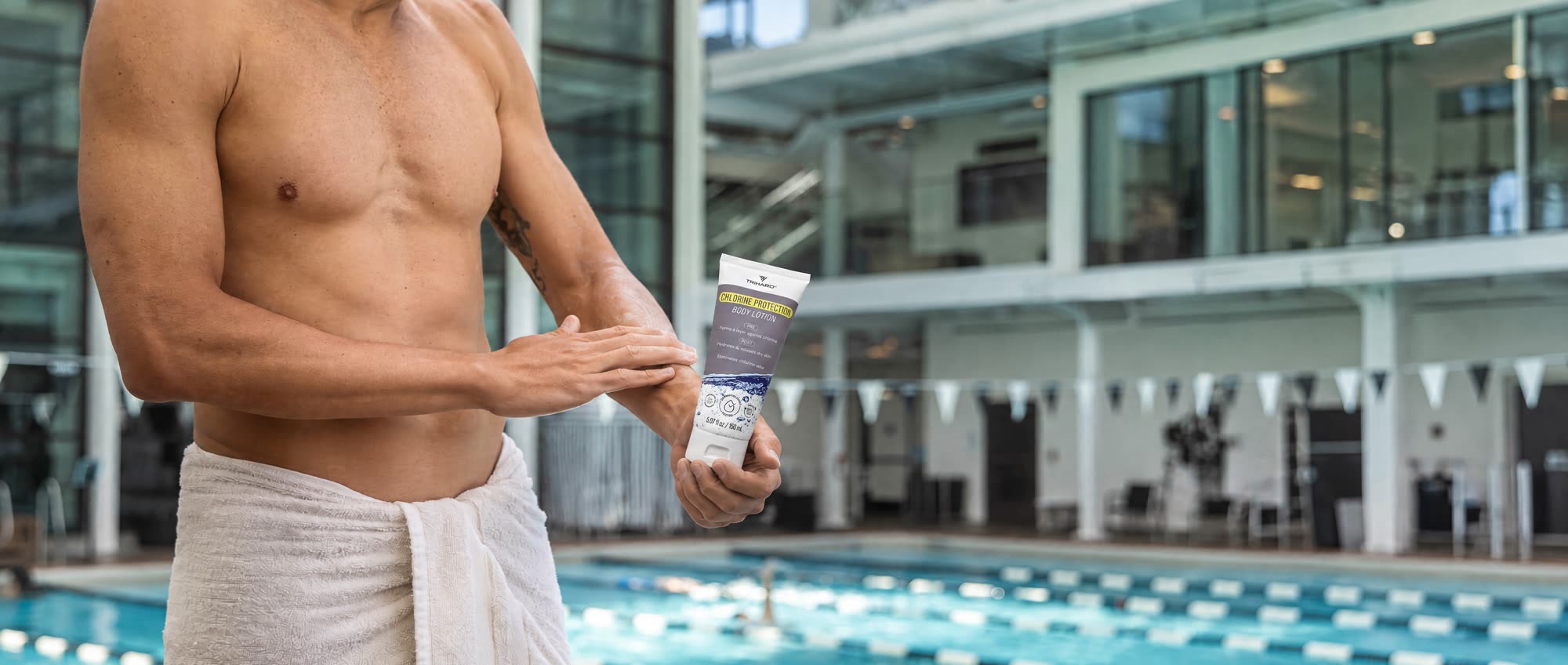 Swimmer applying TRIHARD Chlorine Protection Body Lotion by the pool